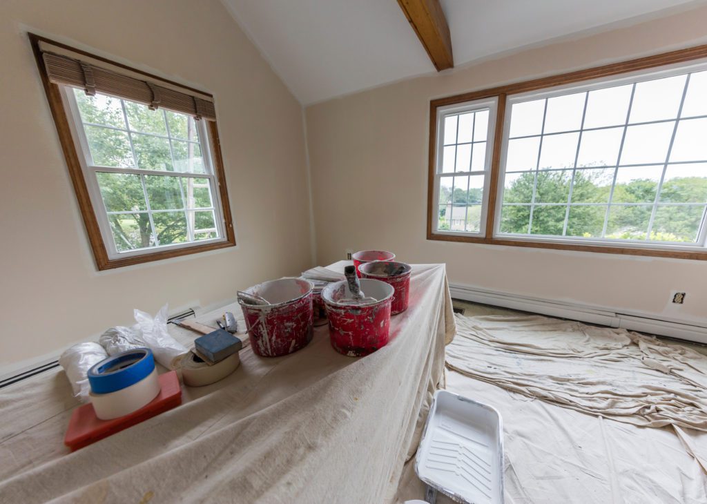 The interior of a home is prepped for paint, and paint supplies are laid out for use