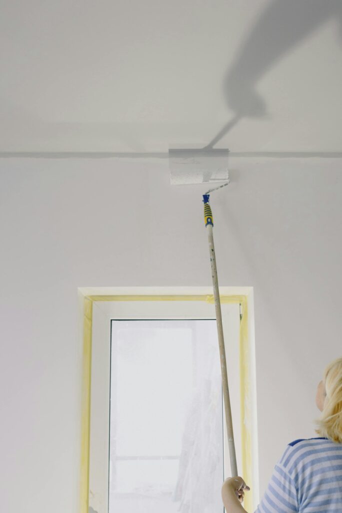 Woman painting a wall during an interior house paint Truckee project using a roller in a residential home.